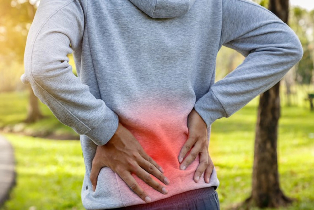 Person holding their lower back in discomfort, highlighting pain that may lead patients to explore spinal decompression therapy for herniated discs